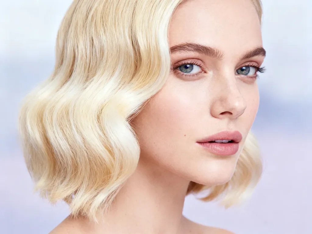 Kobieta z modną koloryzacją typu front blond, prezentująca jasne pasma przy twarzy i delikatne fale.