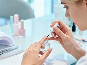 Kobieta delikatnie nakłada naturalny peeling na policzek w jasnej, relaksującej łazience.