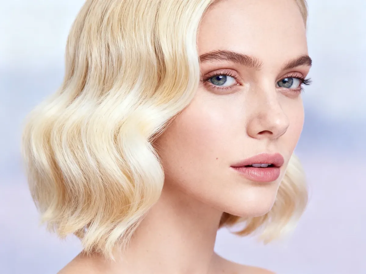 Kobieta z modną koloryzacją typu front blond, prezentująca jasne pasma przy twarzy i delikatne fale.