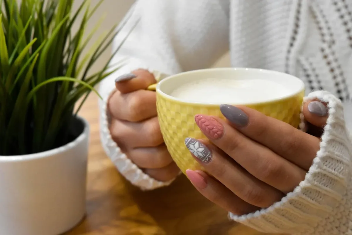 Zadbane dłonie z eleganckim manicure hybrydowym w połyskującym kolorze.